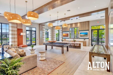 Spacious clubhouse lounge with seating areas, billiards table, and large windows.