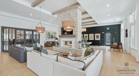 Modern apartment clubroom with stone fireplace, sofas, and pendant lights