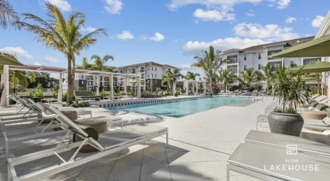 Resort-style apartment pool with palm trees and lounge chairs