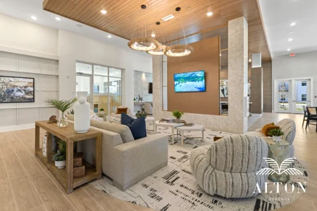 Modern clubhouse lounge with seating, wood ceiling, and mounted TV